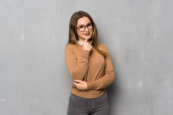 Adolescente fille sur le mur texturé avec des lunettes et sourire
 - Photo, image