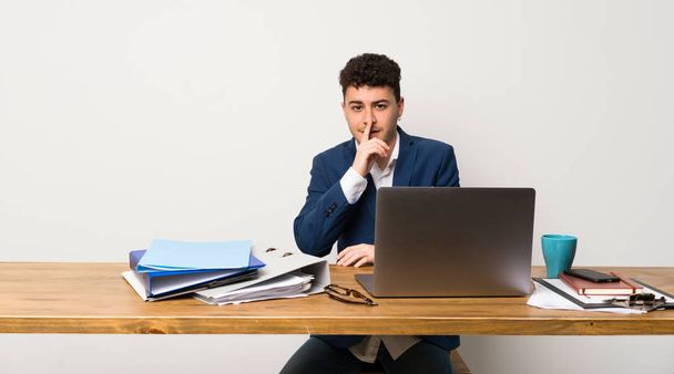 Άνθρωπος των επιχειρήσεων σε ένα γραφείο, δείχνει ένα σημάδι της σιωπής χειρονομία βάζοντας δάχτυλο στο στόμα - Φωτογραφία, εικόνα