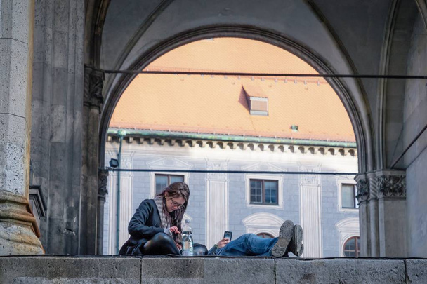 Munich, Germany. February 17, 2019. Couple using gadgets on the architecture background - Foto, afbeelding