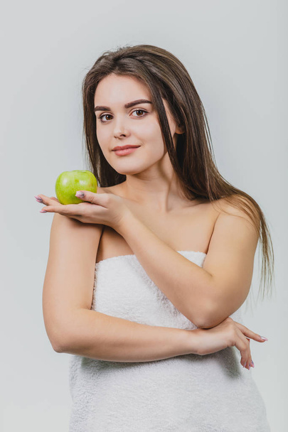 Beautiful young girl with a natural natural make-up and perfect skin with apple in her hand. Beauty face Picture taken in the studio on a white background. - Φωτογραφία, εικόνα