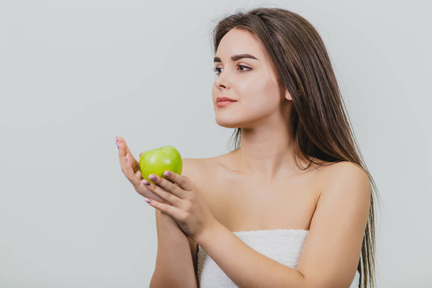 Portrait of an attractive Caucasian girl smiles. Woman isolated on white background. Holds the green apple in hand. Good clean skin. - Photo, image