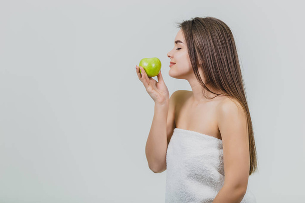 Portrait of an attractive Caucasian girl smiles. Woman isolated on white background. Holds the green apple in hand. Good clean skin. - Foto, Bild