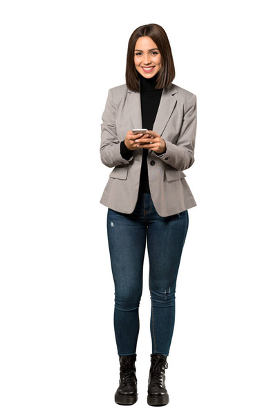 Полнометражный снимок молодой деловой женщины, отправляющей сообщение с мобильного на изолированном белом фоне
 - Фото, изображение