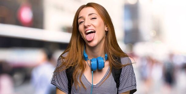 Pelirroja estudiante mujer mostrando lengua en la cámara teniendo divertido mirar en la ciudad
 - Foto, imagen