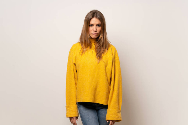 Woman with yellow sweater over isolated wall with sad and depressed expression - Photo, image