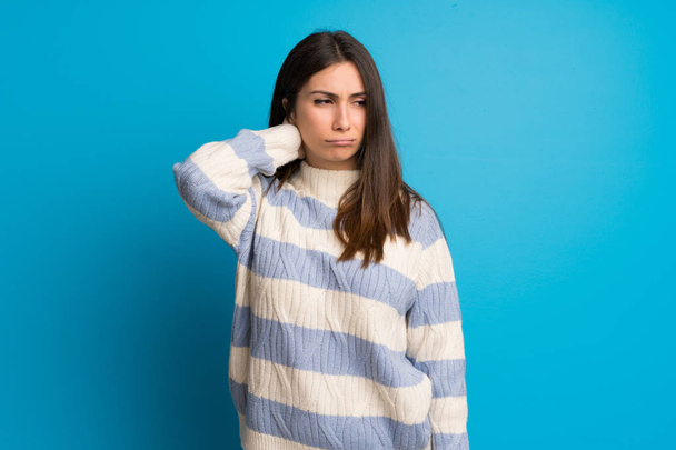 junge Frau mit Nackenschmerzen über blaue Wand - Foto, Bild