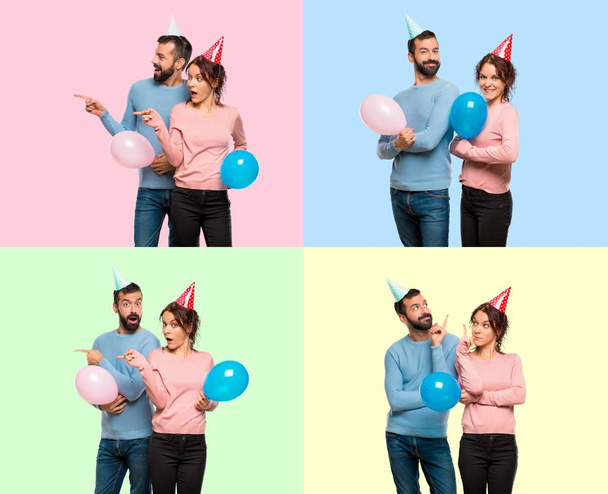 Set of couple with balloons and birthday hats keeping the arms crossed and pointing up and lateral - Photo, Image