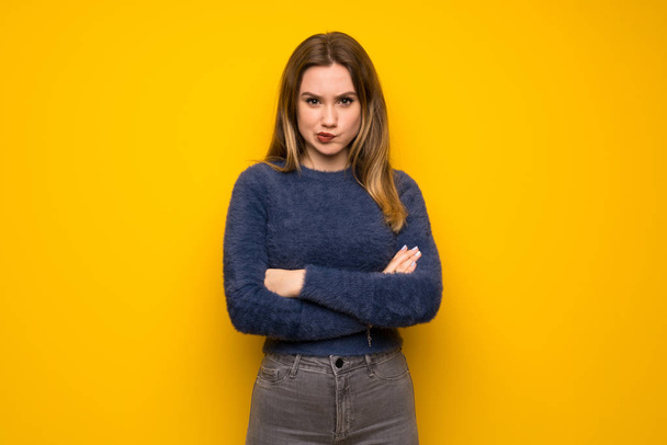 Teenager girl over yellow wall feeling upset - Fotó, kép