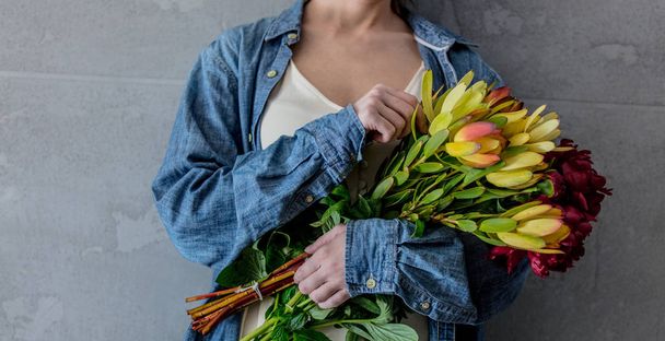 Női kéz, gazdaság csokor pünkösdi rózsa és Leucadendron - Fotó, kép