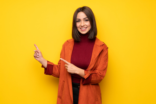 Young woman with coat pointing finger to the side - Photo, Image