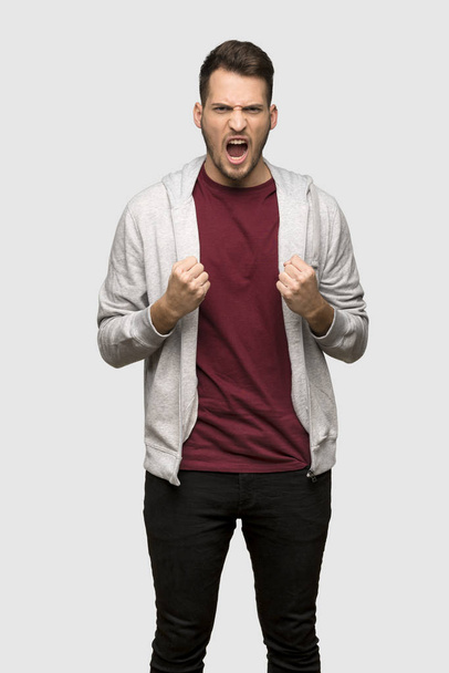 Man with sweatshirt frustrated by a bad situation over grey background - Φωτογραφία, εικόνα