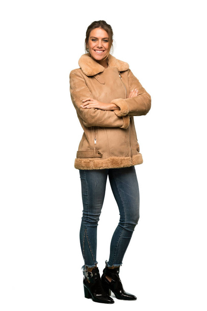A full-length shot of a Blonde woman with a coat with arms crossed and looking forward over isolated white background - Photo, image