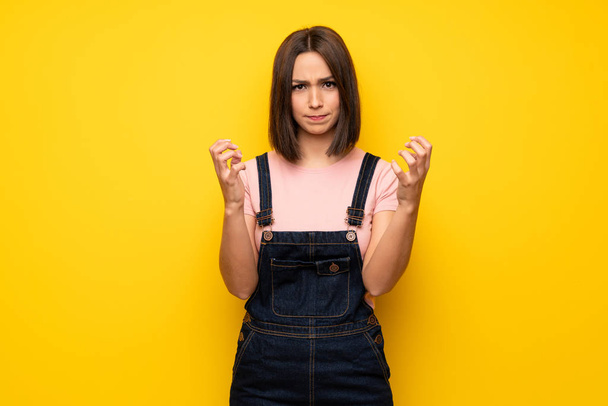 Young woman over yellow wall frustrated by a bad situation - Photo, image