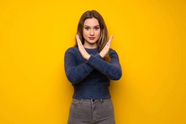 Teenager girl over yellow wall making NO gesture - Fotoğraf, Görsel