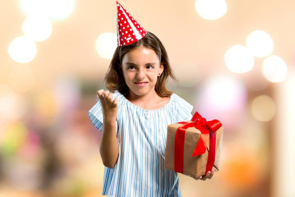 Little girl at a birthday party holding a gift annoyed angry in furious gesture on unfocused background - Fotografie, Obrázek