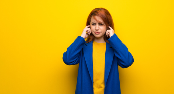 Young redhead woman with trench coat frustrated and covering ears with hands - Photo, Image