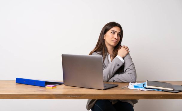 Γυναίκα σε εργασία σε ένα γραφείο που πάσχουν από τον πόνο στον ώμο για να κάνει μια προσπάθεια - Φωτογραφία, εικόνα