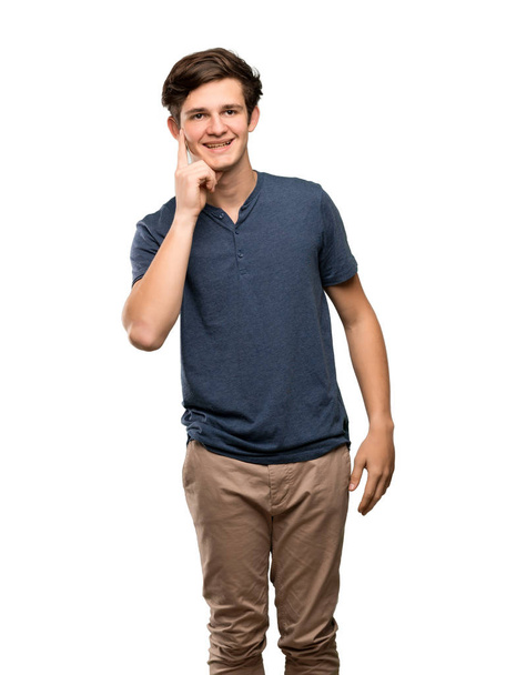 Teenager man thinking an idea while looking up over isolated white background - Foto, afbeelding