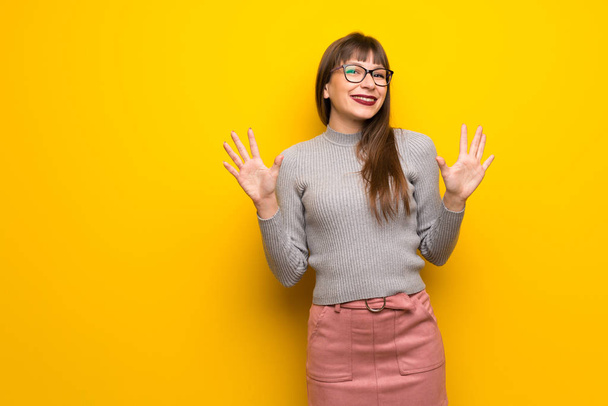 Femme avec des lunettes sur le mur jaune comptant dix avec des doigts
 - Photo, image