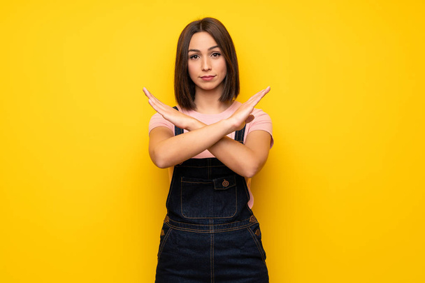 Young woman over yellow wall making NO gesture - Photo, Image