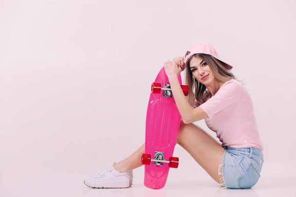 beautiful woman in white t-shirt with pink skateboard - Фото, изображение