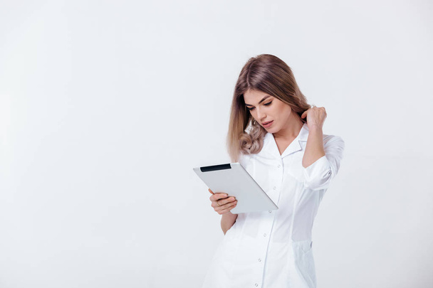 beautiful blonde doctor in white coat using digital tablet - Fotó, kép