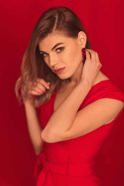 blonde woman posing in red dress on red background - Fotoğraf, Görsel