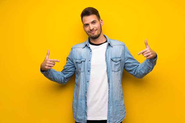 Jóképű férfi, büszke és önelégült sárga falon - Fotó, kép