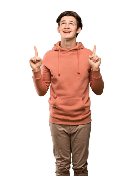 Teenager man with sweatshirt surprised and pointing up over isolated white background - Fotografie, Obrázek