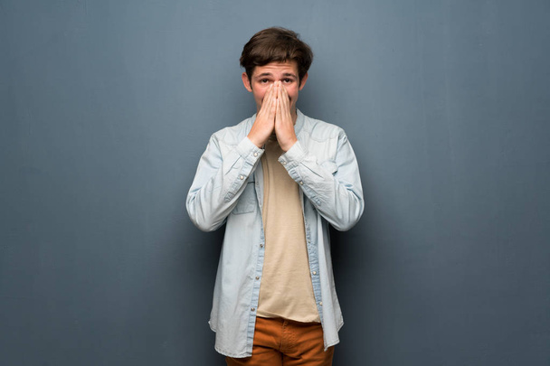 Hombre adolescente con chaqueta de jean sobre la pared gris sonriendo mucho
 - Foto, Imagen
