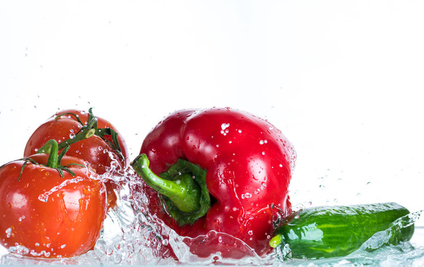 Légumes frais dans une pulvérisation d'eau sur fond blanc, tomate, concombre, poivre doux
 - Photo, image