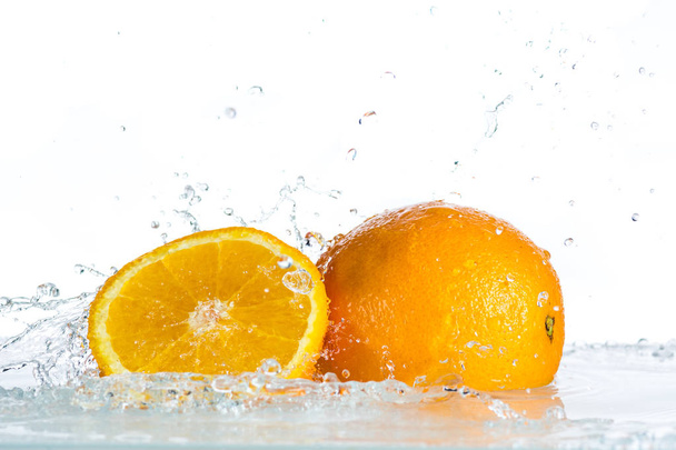 Orange und Grapefruit in einem Wasserstrahl auf weißem Hintergrund - Foto, Bild