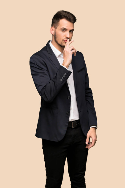 schöner Geschäftsmann zeigt ein Zeichen des Schweigens Geste legt den Finger in den Mund über ockerfarbenen Hintergrund - Foto, Bild