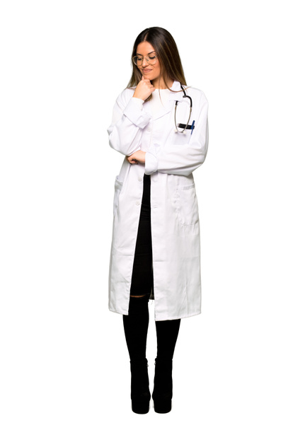 Cuerpo completo de una joven doctora mirando hacia abajo con la mano en la barbilla
 - Foto, imagen