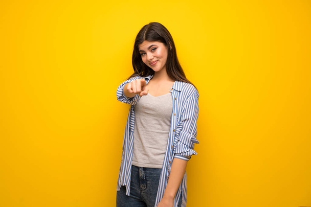 Genç kız sarı duvarın üzerinden parmak seni kendinden emin bir ifadesiyle işaret - Fotoğraf, Görsel