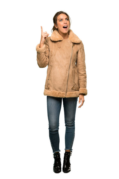 A full-length shot of a Blonde woman with a coat intending to realizes the solution while lifting a finger up over isolated white background - Photo, image