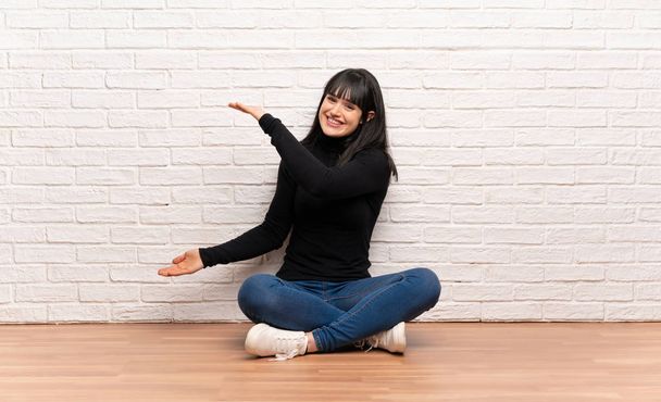 Frau sitzt auf dem Boden und hält Kopierraum, um eine Anzeige zu schalten - Foto, Bild