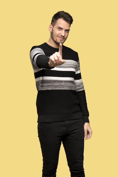 Handsome man showing and lifting a finger over yellow background - Zdjęcie, obraz
