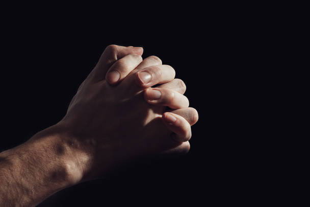 Hand of praying man isolated on black background. - Valokuva, kuva
