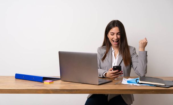 Business woman in a office with phone in victory position - Fotó, kép