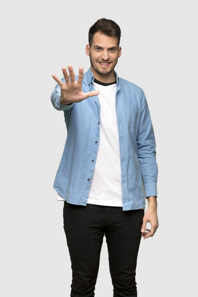 Hombre guapo contando cinco con los dedos sobre fondo gris
 - Foto, imagen