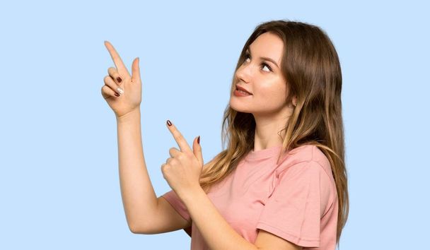 Ragazza adolescente con maglione rosa che punta indietro e presenta un prodotto su sfondo blu isolato
 - Foto, immagini
