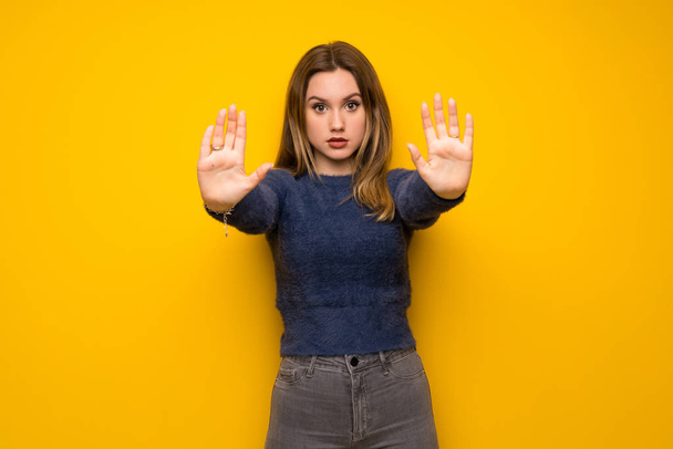 Tiener meisje over gele muur maken stop gebaar en teleurgesteld - Foto, afbeelding