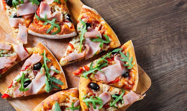 Pizza with Mozzarella cheese, ham, pepper, olive, meat, Tomato sauce, Spices and Fresh arugula. Italian pizza on wooden background - Fotografie, Obrázek