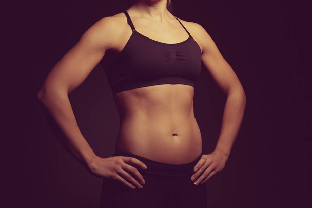 Young sporty woman on dark background - Φωτογραφία, εικόνα