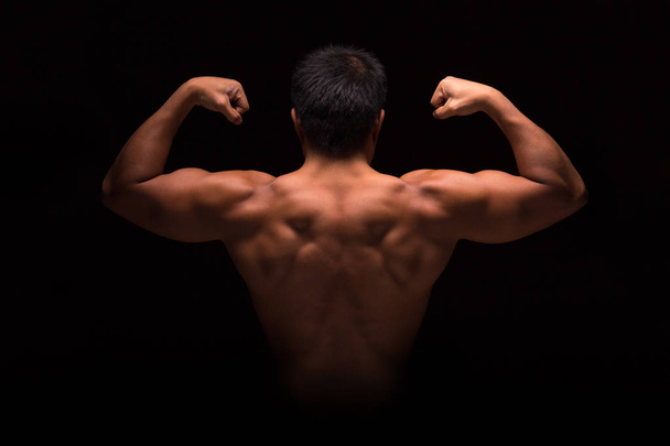 Young strong man posing on dark background - Foto, imagen