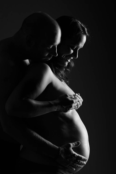 A couple touching baby bump together. Side view, black and white. Close up shot. - Φωτογραφία, εικόνα
