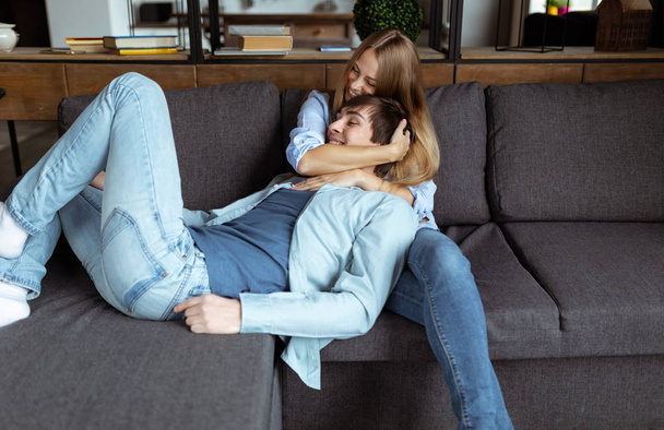 Милая пара отдыхает на диване дома в гостиной
 - Фото, изображение