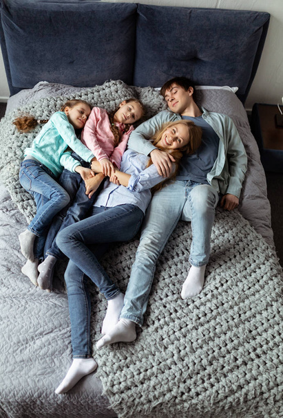 Photo of loving young family of four lying on bed - Фото, изображение