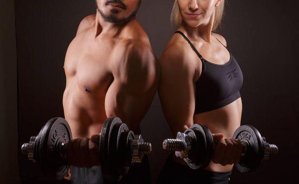 Sporty couple with dumbbells on dark background - Photo, Image